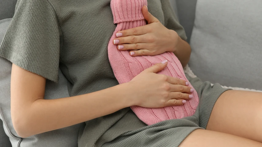 Hot water bottle on abdomen of woman